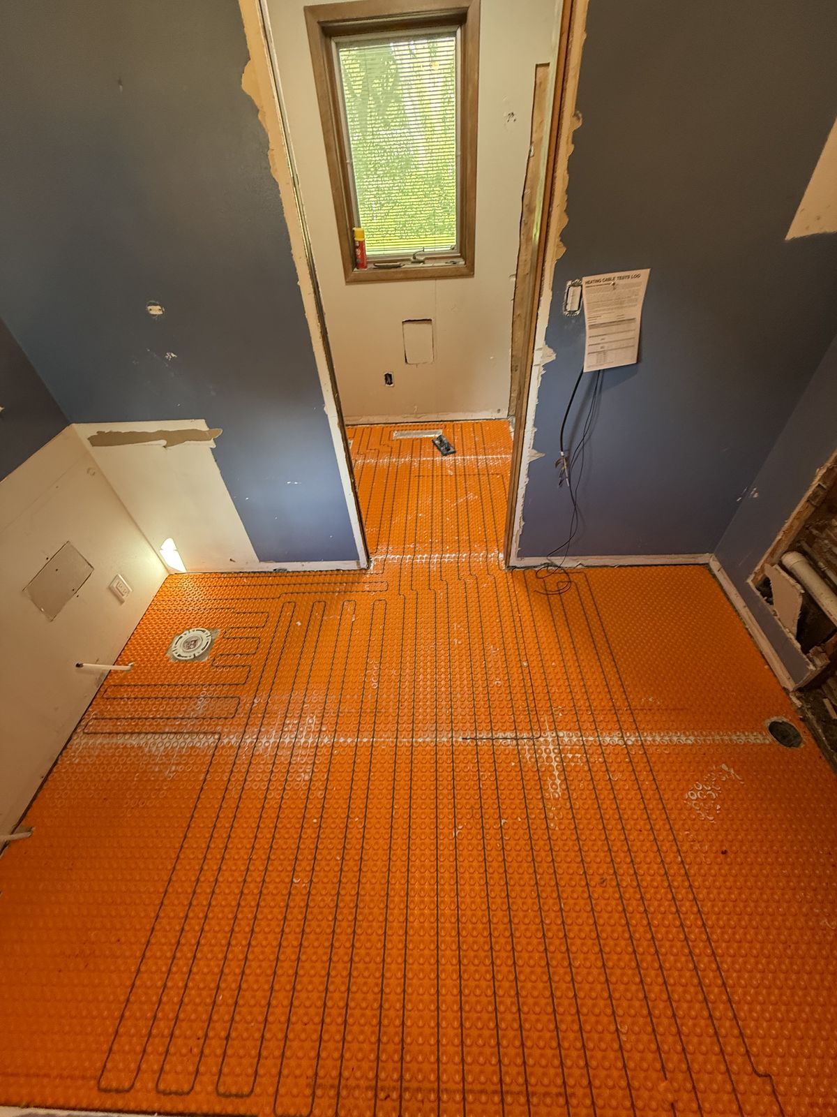 Uncoupling membrane and heated floor cables on bathroom subfloor